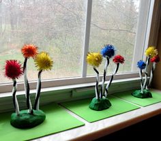 four vases with colorful flowers in them sitting on green paper near a window sill