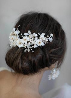 a woman wearing a bridal hair comb with flowers on it's head, in front of a white wall