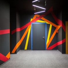 an empty hallway with brightly colored doors and lights on either side of the door,