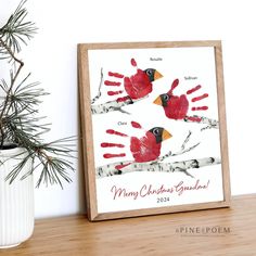 a christmas card with two cardinals on it next to a potted pine tree