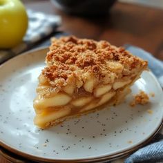 a piece of pie on a plate with an apple in the background