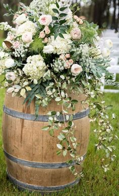 a wooden barrel with flowers and greenery in it sitting on the grass next to an aisle