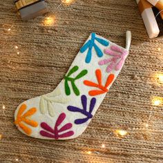 a christmas stocking decorated with multicolored leaves on a table next to presents