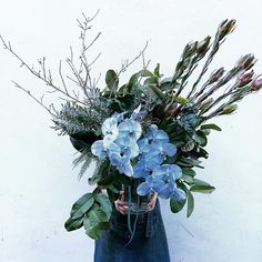 a vase filled with blue flowers and greenery