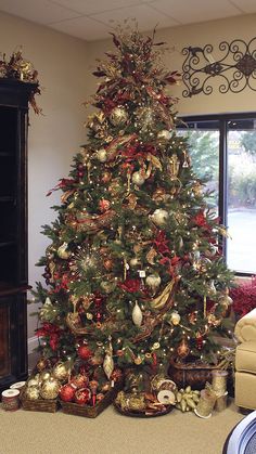 a christmas tree is decorated with red, gold and silver ornaments in a living room