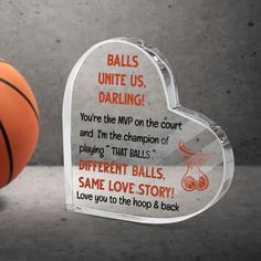 an acrylic heart shaped trophy with a basketball in the background that says balls united, daring