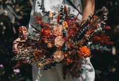 a woman holding a bouquet of flowers in her hands and wearing a white dress with orange accents