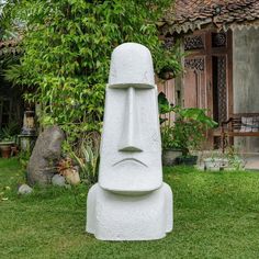 a large white sculpture sitting on top of a lush green field next to a building