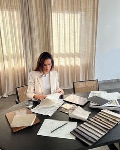 a woman sitting at a table with papers and pens