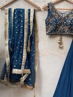 A three-piece teal blue embroidered lehenga set from the Priti Sahni collection. This beautiful georgette teal blue box pleated lehenga is paired with a sequin, and zardozi hand-embroidered blouse. The blouse has a ghungroo tassel tie-up at the back. And the lehenga has an embroidered belt to the waistline. This outfit is completed with a sequined work net dupatta. Blue Sets With Sheer Dupatta In Traditional Drape, Blue Traditional Drape Sets With Sheer Dupatta, Traditional Blue Sets With Sheer Dupatta, Blue Chanderi Pre-draped Saree With Intricate Embroidery, Blue Sheer Dupatta Set For Navratri, Blue Anarkali Style Pre-draped Floor-length Saree, Blue Dola Silk Pre-draped Saree For Reception, Transitional Season Blue Anarkali Lehenga, Blue Chanderi Sets For Reception