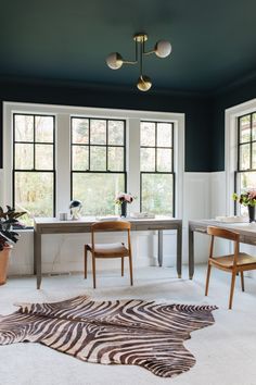 a dining room with zebra rugs on the floor and two windows in the background