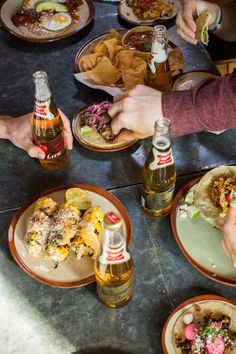 several people sitting at a table with plates of food and drinks