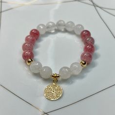 Strawberry quartz round bracelet with white quartz faceted stones and gold plated charm. Gemstone sizes 10mm. Handmade with durable stretch elastic string.  Size 7.5 inches, approximate. It is believed that the Strawberry quartz stone promotes life & growth along with love & affection. It enlightens your Heart Chakra and is the stone of Joy. CARE INSTRUCTIONS:  Take it off before bathing, exercising, swimming. Keep your bracelet in a dry place.  Don't wear it in a wet environment such as a pool White Rose Quartz Beaded Bracelets With Round Beads, White Charm Bracelet With Faceted Round Beads, White Rose Quartz Crystal Bracelet With Gemstone Beads, Rose Quartz Natural Stones Round Bracelets, Round Rose Quartz Crystal Bracelet, Rose Quartz Gemstone Round Bracelet, White Rose Quartz Crystal Bracelet With Round Beads, White Rose Quartz Beaded Bracelets, White Rose Quartz Bracelets With Round Beads