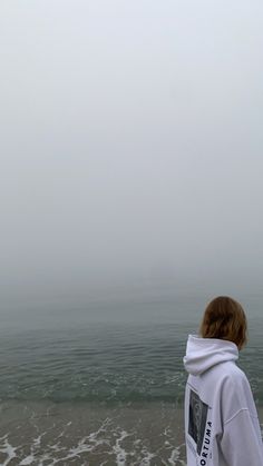 a person standing on the beach looking out at the water