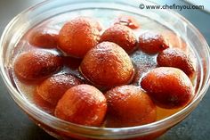 a glass bowl filled with oranges on top of a table