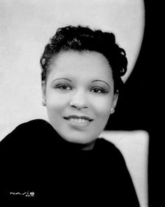 a black and white photo of a woman with short hair wearing a black shirt smiling