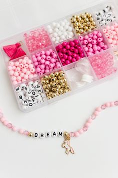 a beaded necklace with beads and charms in it on a white surface next to the word dream