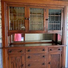 a wooden cabinet with glass doors and drawers