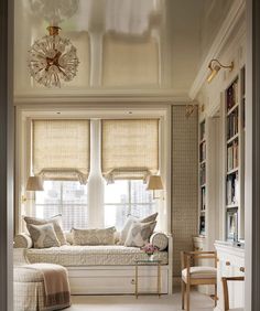 a living room filled with furniture and windows covered in roman blind shades on top of them