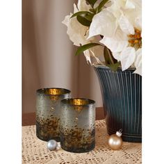 two vases with flowers in them sitting on a table next to some pearls and other decorations