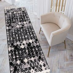 a black and white runner rug in the middle of a room with a chair next to it