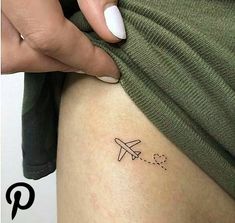 a woman's leg with a small airplane tattoo on the side of her thigh