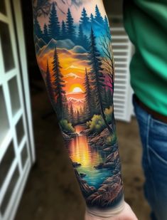 a person with a tattoo on their arm that has a lake and trees in it