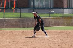 a woman in black and white baseball uniform on a field with catchers mitt