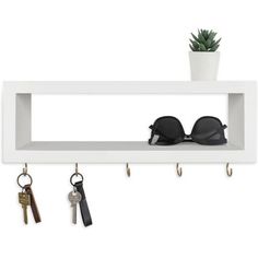 a white shelf with two pairs of sunglasses and keys hanging on hooks next to a potted plant