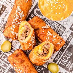 some food is laying out on a newspaper next to a bowl of mustard and dipping sauce