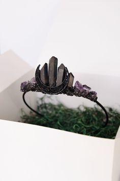 a tiara with amethyst crystals in it sitting on top of a box