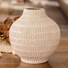 a white vase sitting on top of a wooden table next to a piece of cloth