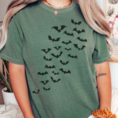 "Bats Halloween comfort Colors Tee, Bats Tee, Trendy Comfort colors Halloween Shirts, Witchy Shirts, Orange comfort color halloween shirt IMPORTANT:  Please read all details below! We want you to be completely happy with your purchase! 🌿 M A T E R I A L S This is an adult unisex COMFORT COLORS BRAND T SHIRT, IT IS 100% RING SPUN COTTON. 🌿 P R I N T I N G: Our shirts are made with Direct to garment printing, not vinyl! Which means your print will last longer and no peeling or cracking! It gives more of a faded vintage type look. 🌿 S I Z I N G THIS T SHIRT IS UNISEX SIZING, HOWEVER IF YOU LIKE THE \"OVERSIZED\" LOOK PLEASE SIZE UP 1-3 SIZES. For reference we recommend taking one of your favorite T SHIRTS and lay It flat to measure (armpit to armpit for width and top to bottom for length), Casual Green Halloween Top, Grunge Short Sleeve Halloween Shirt, Grunge Short Sleeve Shirt For Halloween, Spooky Cotton Top For Halloween, Halloween Grunge Cotton Shirt, Spooky Cotton Halloween Top, Grunge Cotton Halloween Shirt, Grunge Cotton Shirt For Halloween, Casual Short Sleeve Shirt For Halloween