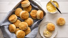 some biscuits and butter are on a table next to a bowl of cream cheese sauce