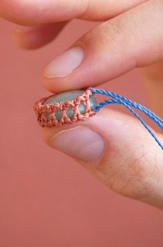 a hand holding a piece of string with a ring on it