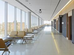 an empty waiting area with chairs and windows in the background, along with a clock on the wall