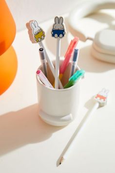 a cup filled with pens and markers on top of a table