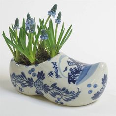 a blue and white bird planter with flowers in it