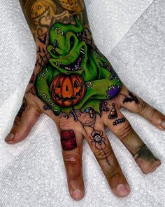 a person's hand with tattoos on it and an orange jack - o - lantern