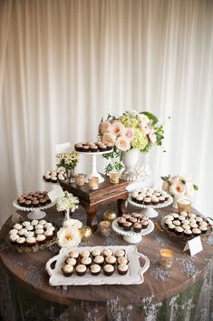 a table topped with lots of cupcakes next to a vase filled with flowers