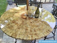 a table made out of wine corks with two bottles on it and an umbrella in the middle