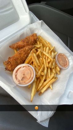 fried chicken and french fries in a takeout container with dipping sauce on the side