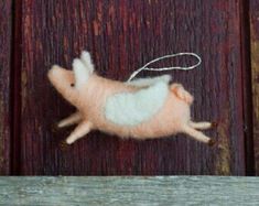 a needle - felt pig ornament hanging on a wooden door with a string attached to it