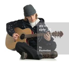 a young man sitting on the ground playing an acoustic guitar with headphones in his ears