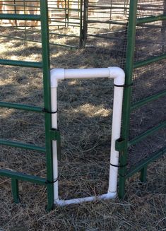 an animal pen with some white pipes in it