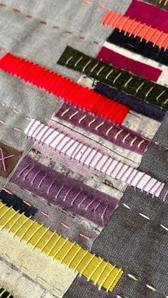 an assortment of different colored threads on a piece of fabric with stitching in the middle