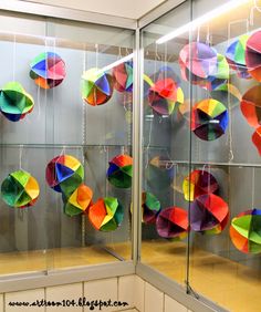 there are many colorful umbrellas hanging in the glass display case on the wall behind them