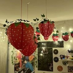 three paper strawberries hanging from the ceiling in a room decorated with lights and decorations