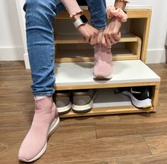 a person sitting on top of a shelf with their feet in the air and wearing pink shoes