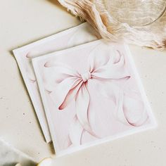 two cards with pink bows on them sitting next to a vase and some other items